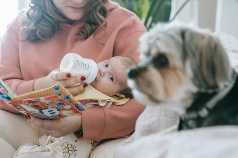 a woman sitting on a couch feeding a baby with a bottle, by Emma Andijewska, pexels contest winner, subject: dog, avatar image, detail shot, fashionable