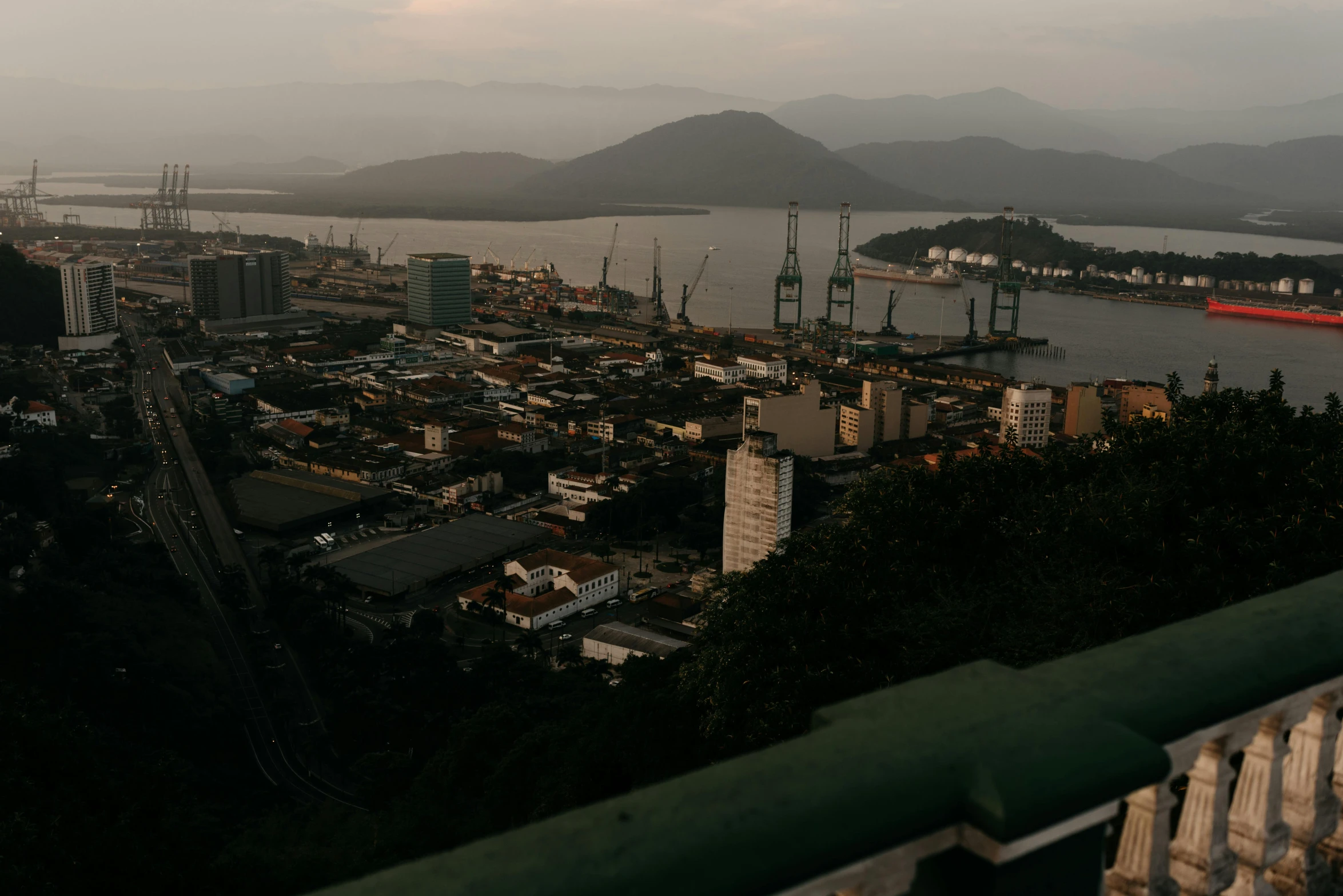 a view of a city from the top of a hill, pexels contest winner, port scene background, moody morning light, “ aerial view of a mountain, tropical coastal city