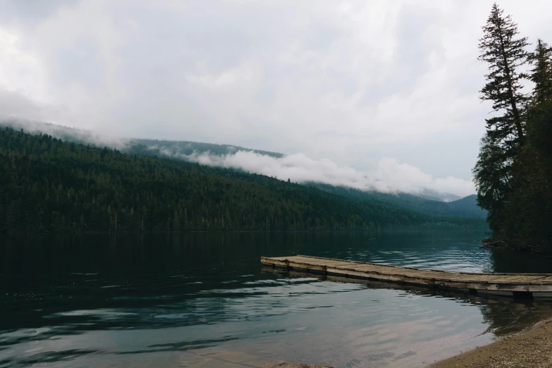 a dock sitting on top of a lake next to a forest, by Jessie Algie, pexels contest winner, overcast gray skies, 2 5 6 x 2 5 6 pixels, evergreen valley, covered in clouds