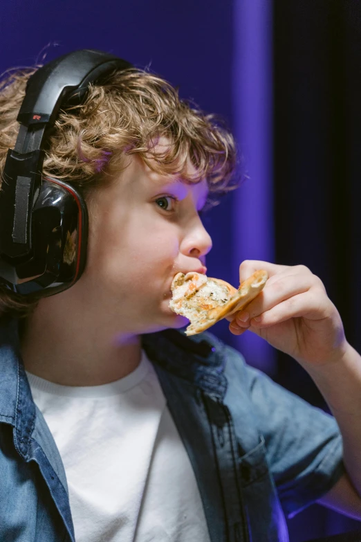 a young boy wearing headphones eating a piece of pizza, immersive, epk, in a taco bell, studio spotlight