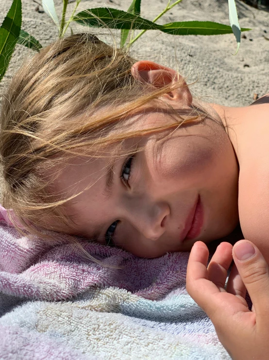 a little girl laying on a towel on the beach, by Niko Henrichon, profile picture, lovingly looking at camera, taken in 2 0 2 0, selfie photo