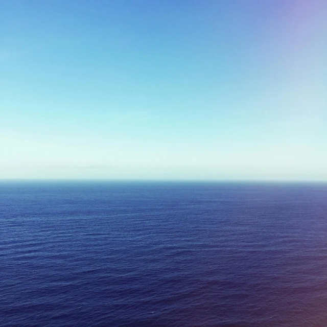 a large body of water next to a beach, unsplash, minimalism, gradient blue, 2 5 6 x 2 5 6 pixels, viewed from very far away, horizon forbideen west