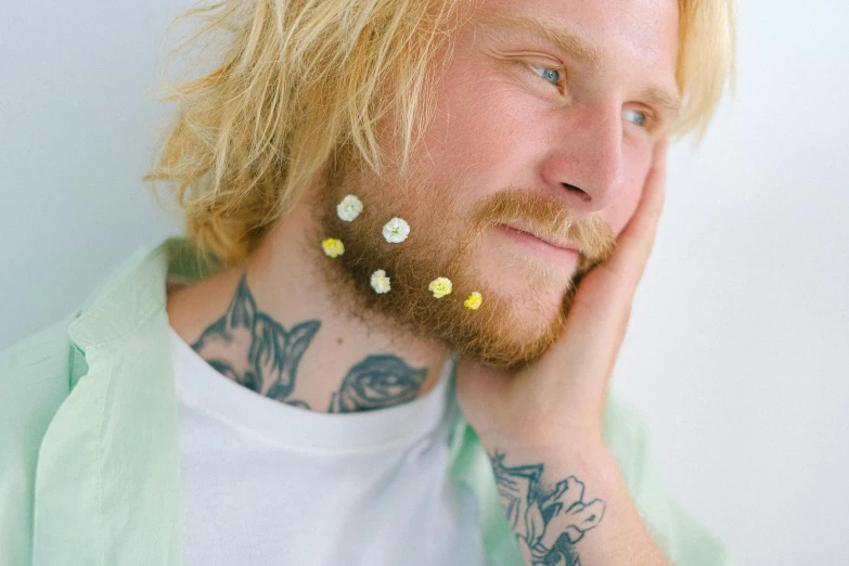 a man with tattoos and piercings on his face, an album cover, inspired by Elsa Bleda, trending on pexels, daisies, blond beard, pressed flowers, earbuds jewelry