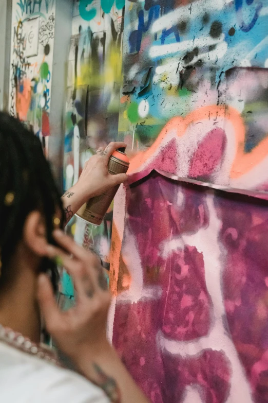 a woman standing in front of a wall covered in graffiti, by artist, trending on pexels, action painting, in a workshop, painting on a badge, paints mixing, looking across the shoulder