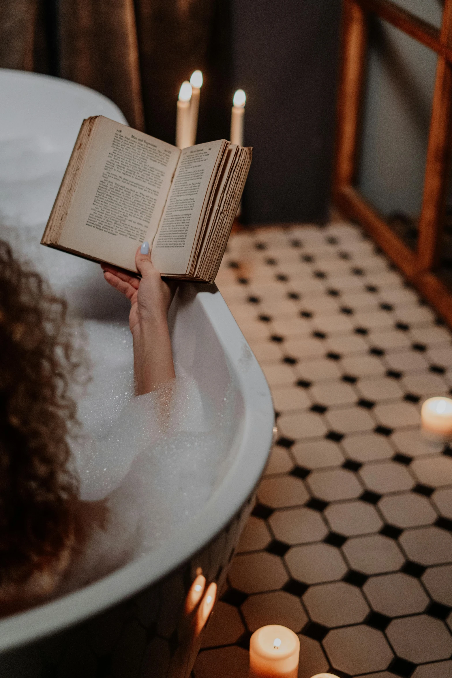 a woman reading a book in a bathtub with candles, inspired by William Stott, pexels contest winner, with book of science, vintage inspired, tall, close angle