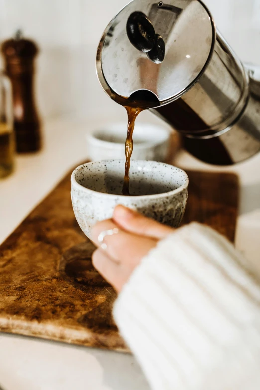 a person pouring a cup of coffee into a bowl, trending on pexels, earthy, made of glazed, scandinavian, manuka