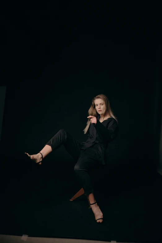 a woman in a black suit is dancing in the dark, by Sara Saftleven, pexels contest winner, realism, karate pose, sydney sweeney, studio medium format photograph, casual pose