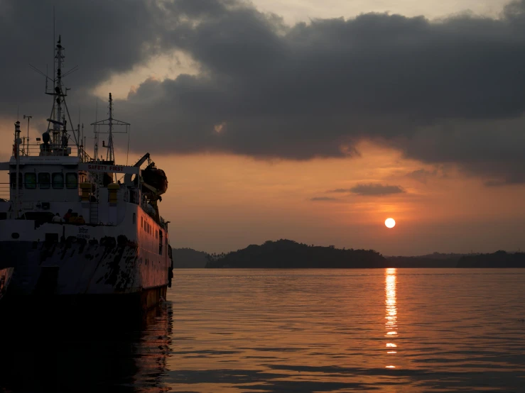 a boat that is sitting in the water, by Joseph Severn, pexels contest winner, sumatraism, sun setting, from side, grey, subtitles