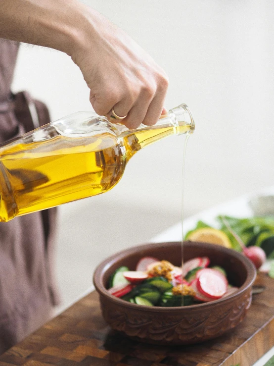 a person pouring olive oil into a bowl of vegetables, by Julia Pishtar, detailed product image, full-body, brown, displayed