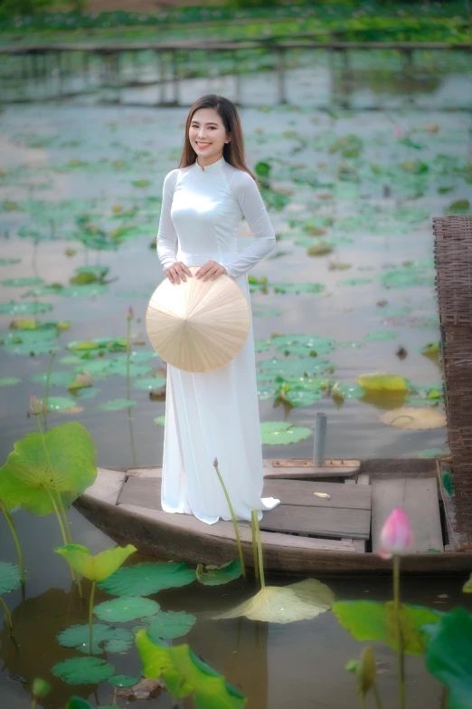 a woman standing on a boat in a body of water, a picture, inspired by Cui Bai, ao dai, 15081959 21121991 01012000 4k, square, standing on a lotus