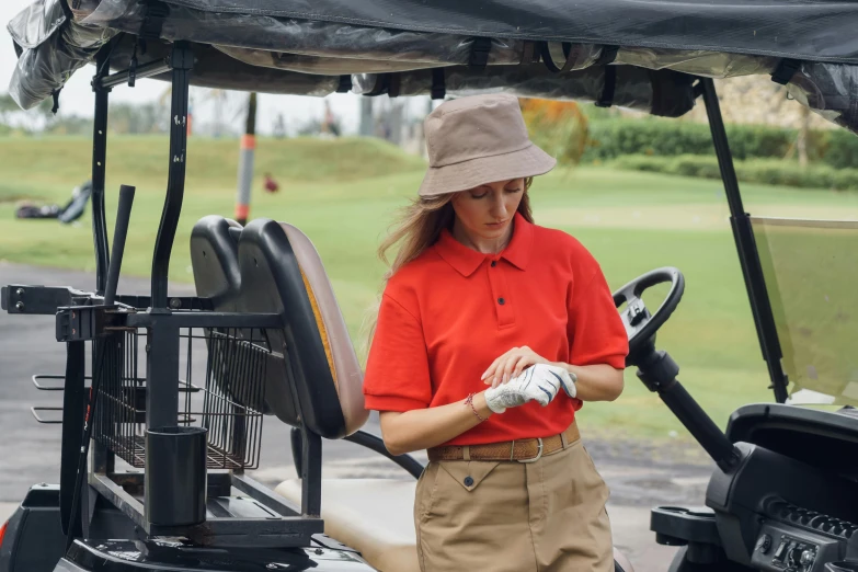 a woman standing next to a golf cart, pexels contest winner, red ascot and a field cap, inspect in inventory image, worksafe. instagram photo, red sport clothing