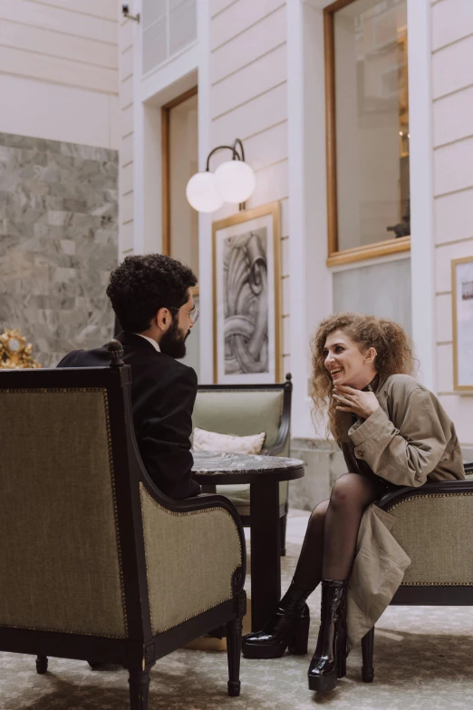 a man and a woman sitting at a table in a lobby, pexels contest winner, flirting, sitting in an armchair, low quality photo, caucasian