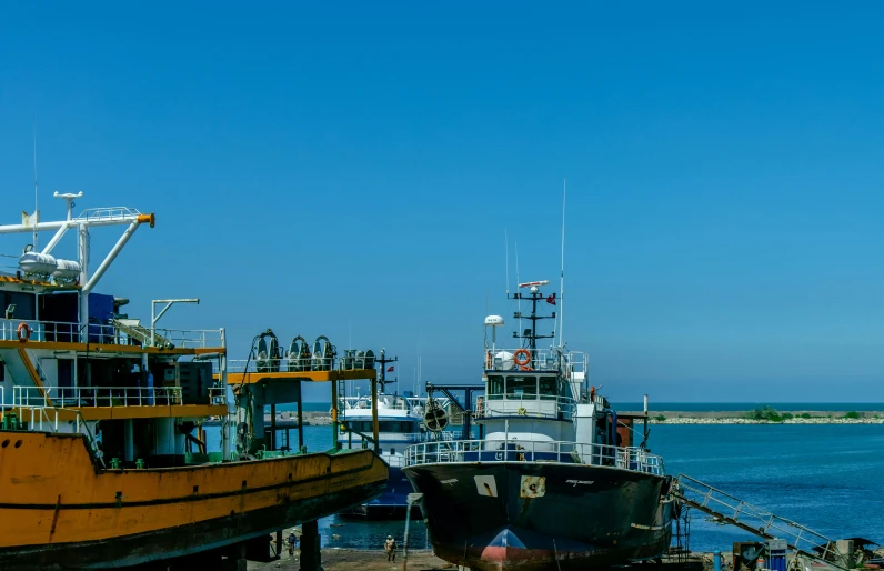 a couple of boats that are sitting in the water, pexels contest winner, hurufiyya, shipping docks, blue sky, thumbnail, ground level shot
