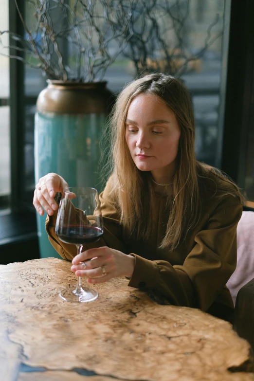 a woman sitting at a table with a glass of wine, a portrait, by Jesper Knudsen, pexels contest winner, sydney sweeney, gif, pouring, comfortable atmosphere