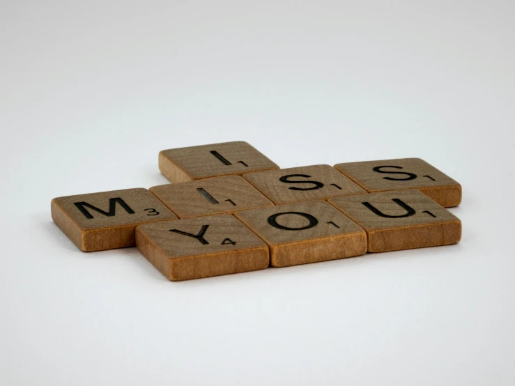 wooden scrabbles spelling i miss you on a white background, by Sylvia Wishart, unsplash, 1920s photograph, alessio albi, brick, mid-20s