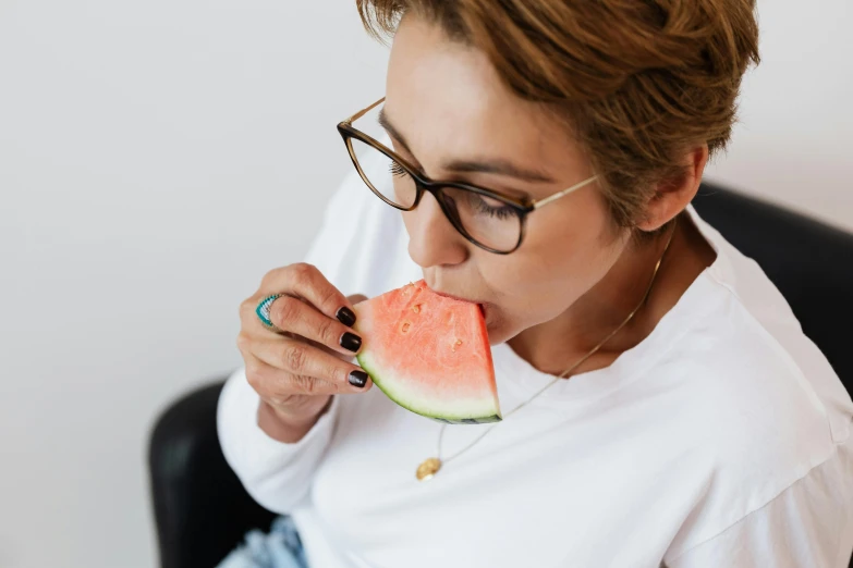 a woman sitting in a chair eating a slice of watermelon, by Julia Pishtar, pexels contest winner, wearing black rimmed glasses, chewing tobacco, profile image, natasha tan maciej kuciara