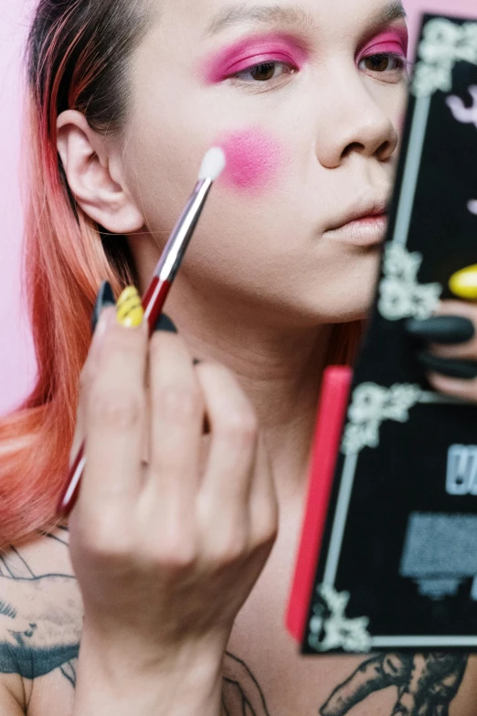 a woman holding a book in front of her face, an album cover, trending on pexels, pop art, holding paintbrushes, popular south korean makeup, pink and yellow, punk inspired