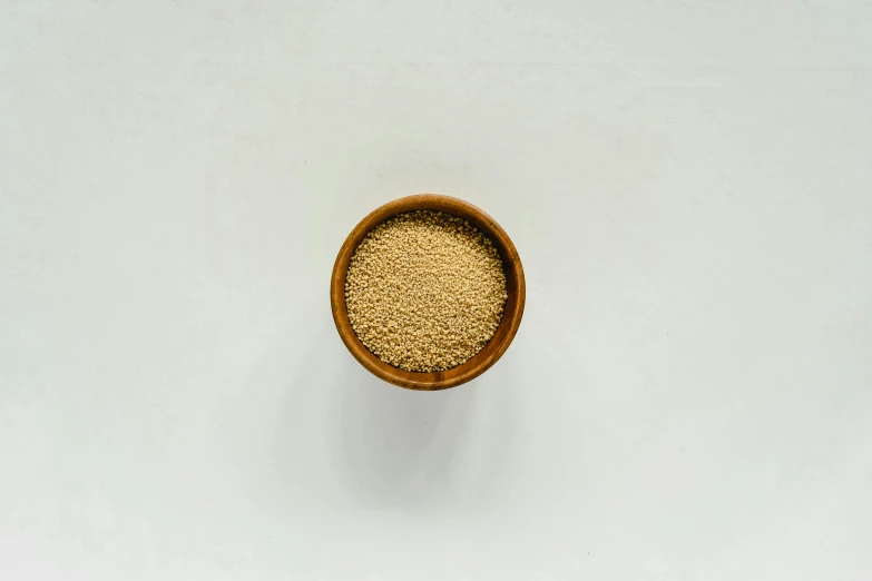 a bowl of sesame seeds on a white surface, a stipple, unsplash, detailed product image, sand color, shot on sony a 7, made of spaghetti