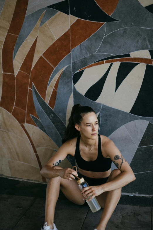 a woman sitting on the ground with a bottle of water, a portrait, by Jessie Alexandra Dick, pexels contest winner, process art, in a gym, aboriginal australian hipster, crop yoga short, beautiful tilework