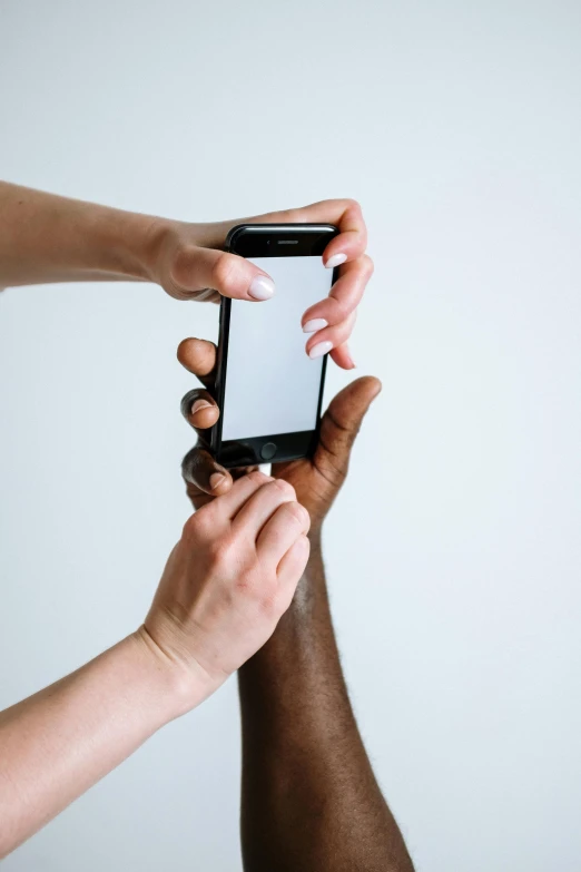 a group of people holding up a smart phone, a black and white photo, trending on pexels, gradient brown to white, single pair of hands, man is with black skin, 2 people