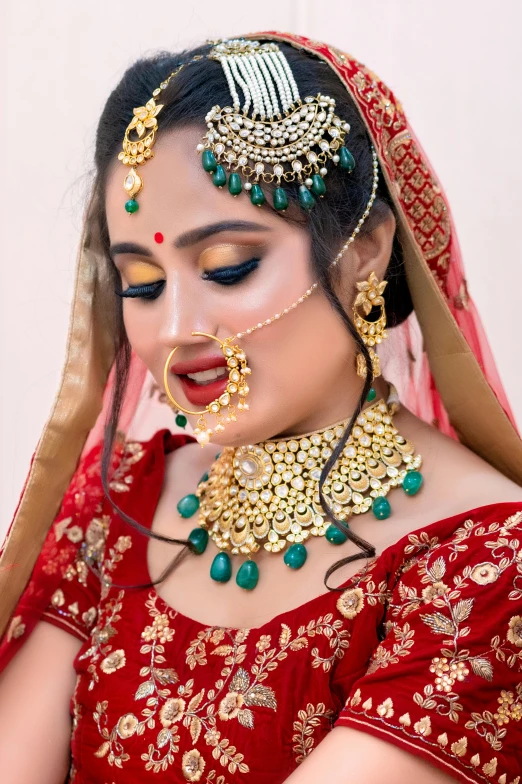 a woman in a red dress and gold jewelry, inspired by Saurabh Jethani, pexels contest winner, wearing elaborate green and gold, red lipstick on face, thumbnail, bride