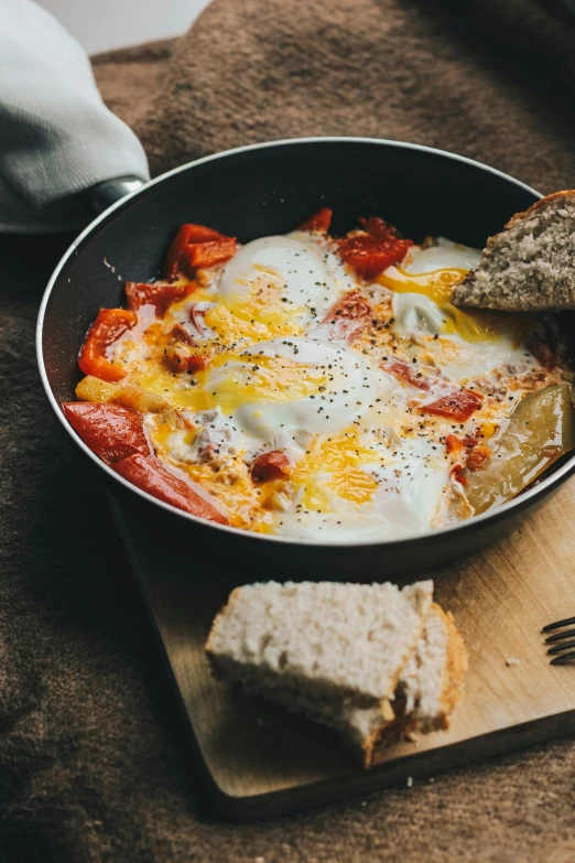 a pan filled with eggs on top of a wooden cutting board, by Adam Marczyński, pexels contest winner, ratatouille style, breakfast at las pozas, foil, cosmopolitan