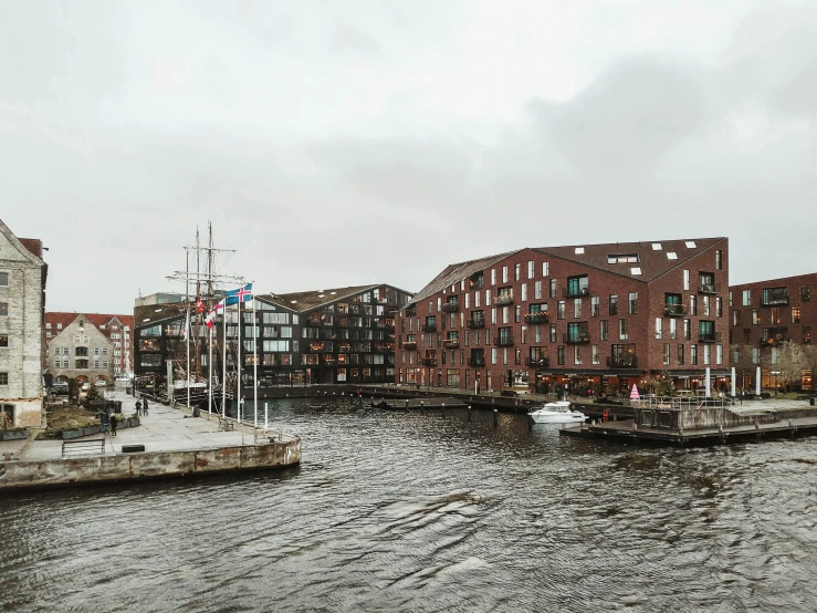 a river filled with lots of boats next to tall buildings, a photo, inspired by Wilhelm Marstrand, pexels contest winner, modernism, industrial architecture, while it's raining, brown, denmark