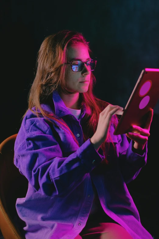 a woman sitting in a chair using a laptop, a hologram, trending on pexels, purple jacket, wearing red tainted glasses, holding controller, standing with a black background