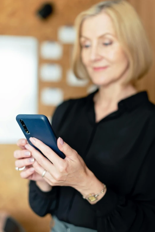 a woman in a black shirt holding a cell phone, zoomed in, digital image, older woman, information