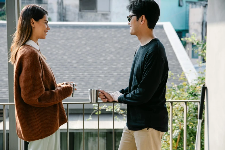 a man standing next to a woman on a balcony, pexels contest winner, long sleeves, south korean male, movie scene, two cups of coffee