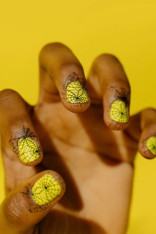 a close up of a person's hand with yellow nail polish, net art, african fractals, ink on skin, antennae, ignant