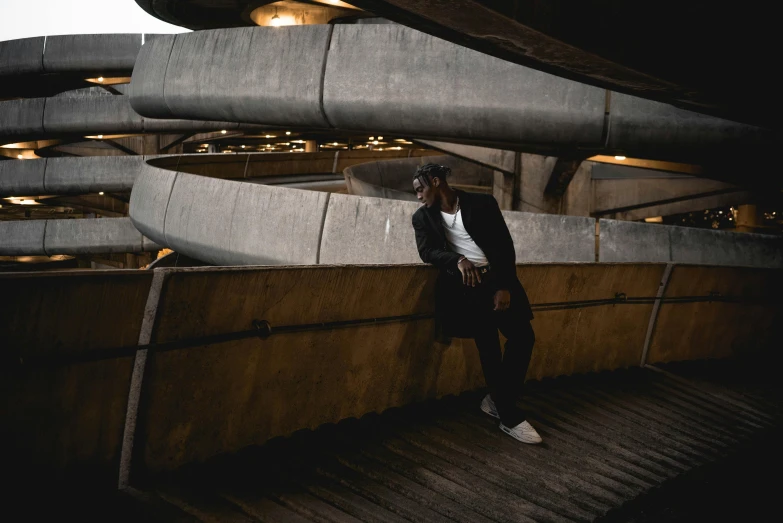 a man in a tuxedo leaning against a wall, by Sam Charles, pexels contest winner, brutalism, sitting under bridge, lil uzi vert, black. airports, in an arena pit