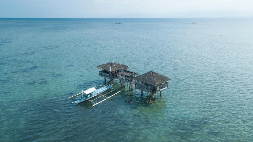 a couple of boats sitting on top of a body of water, hut, overlooking the ocean, aerial, manila