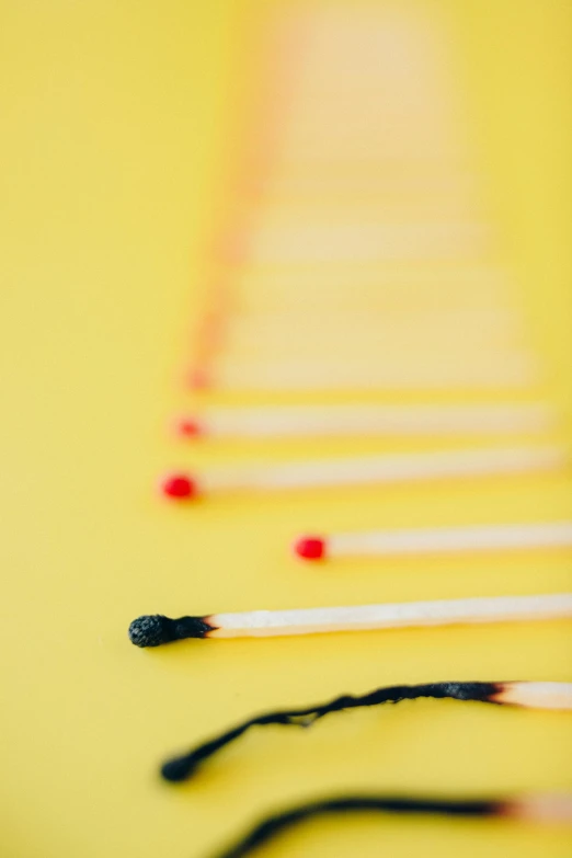 a row of matches sitting on top of a table, inspired by Barnett Newman, pexels contest winner, process art, on a yellow canva, playing with fire, detail shot, tiny sticks