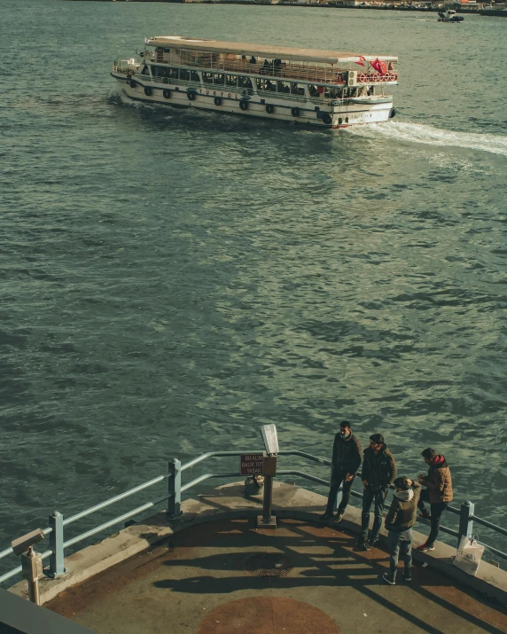 a group of people standing on top of a pier next to a body of water, on a boat