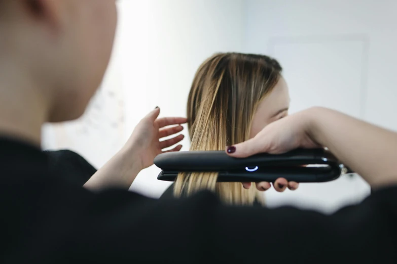 a woman is straightening her hair in front of a mirror, smooth streamline, slightly pixelated, colour corrected, thumbnail