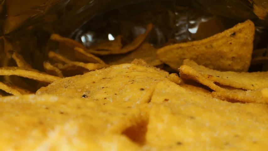 a close up of a bag of chips, by Carey Morris, pexels, process art, chilaquiles, yellow and black, looking across the shoulder, light source from the left