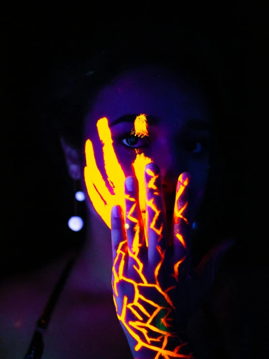 a woman covering her face with neon paint, inspired by Elsa Bleda, pexels contest winner, glowing veins, with glowing yellow eyes, profile image, glowing aztec tattoos