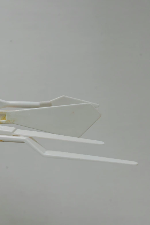 a paper airplane sitting on top of a table, inspired by Zaha Hadid, detail structure, robotic extended arms, on vellum, bone