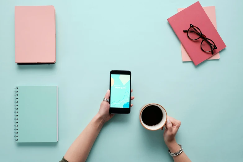 a person holding a smart phone next to a cup of coffee, trending on unsplash, pink and teal, 9 9 designs, minimalist photo, schools