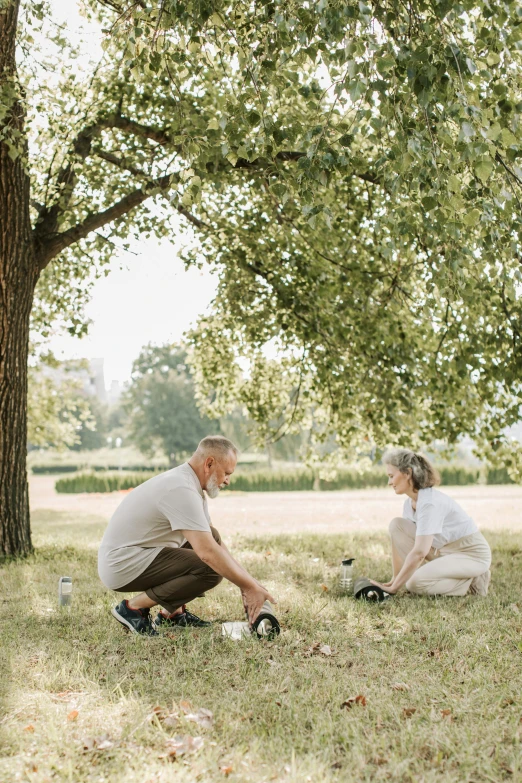 a couple of people that are sitting in the grass, next to a tree, gardening, profile image, picnic