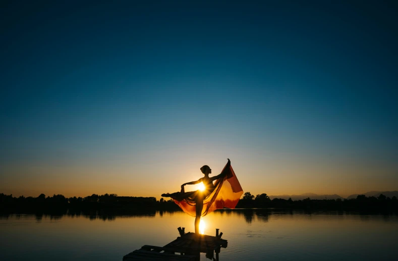 a person standing on top of a body of water, by Julia Pishtar, pexels contest winner, sacral chakra, pointe pose, artisanal art, summer evening