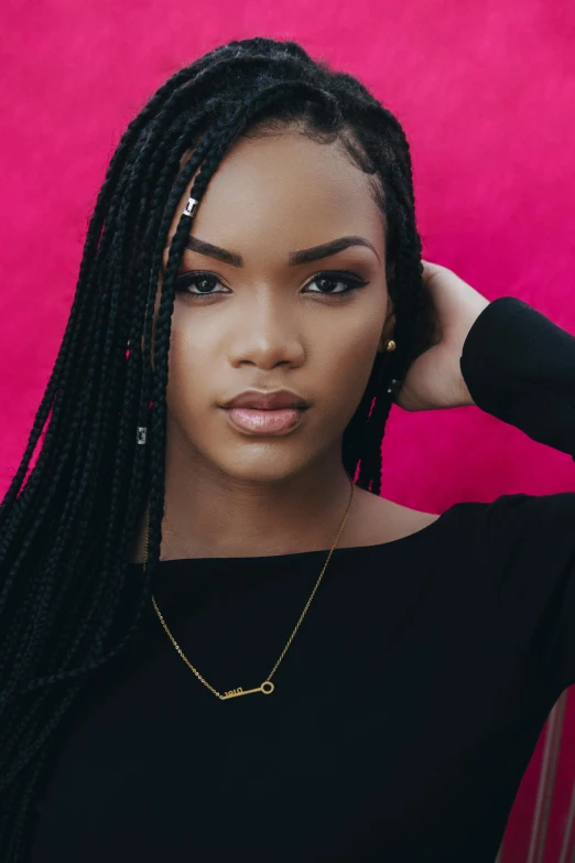 a woman with long black hair standing in front of a pink wall, inspired by Theo Constanté, trending on pexels, braids, zendaya, jewelry, african american young woman