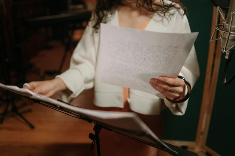 a woman holding a sheet of paper in front of a microphone, pexels, sheet music, white sleeves, writing on a clipboard, avatar image