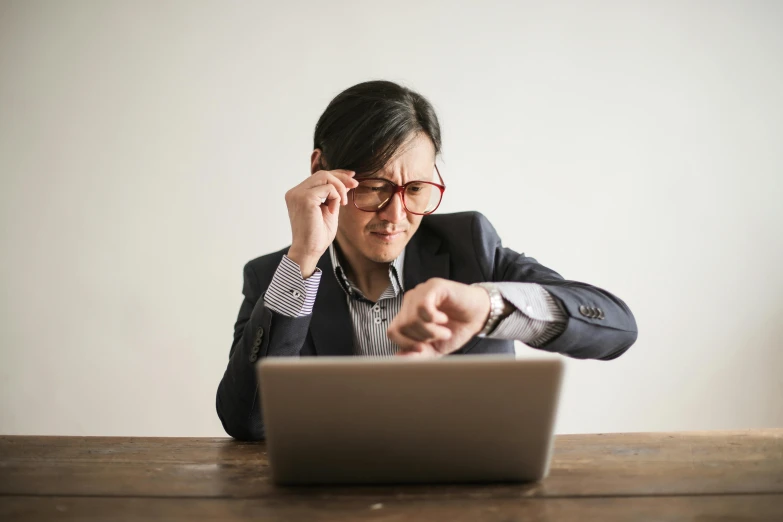 a woman sitting at a table in front of a laptop, by Carey Morris, pexels, holding a pocket watch, wearing square glasses, avatar image, li zixin