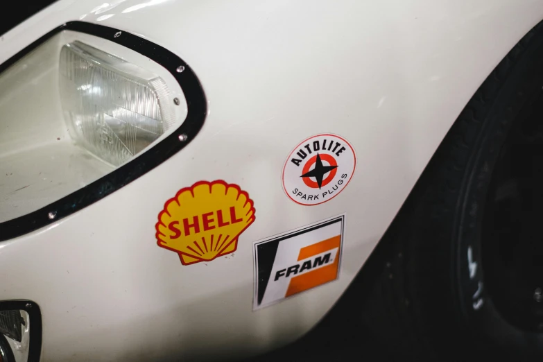 a close up of a car with stickers on it, unsplash, shell, vintage race footage, detailed white, enamel