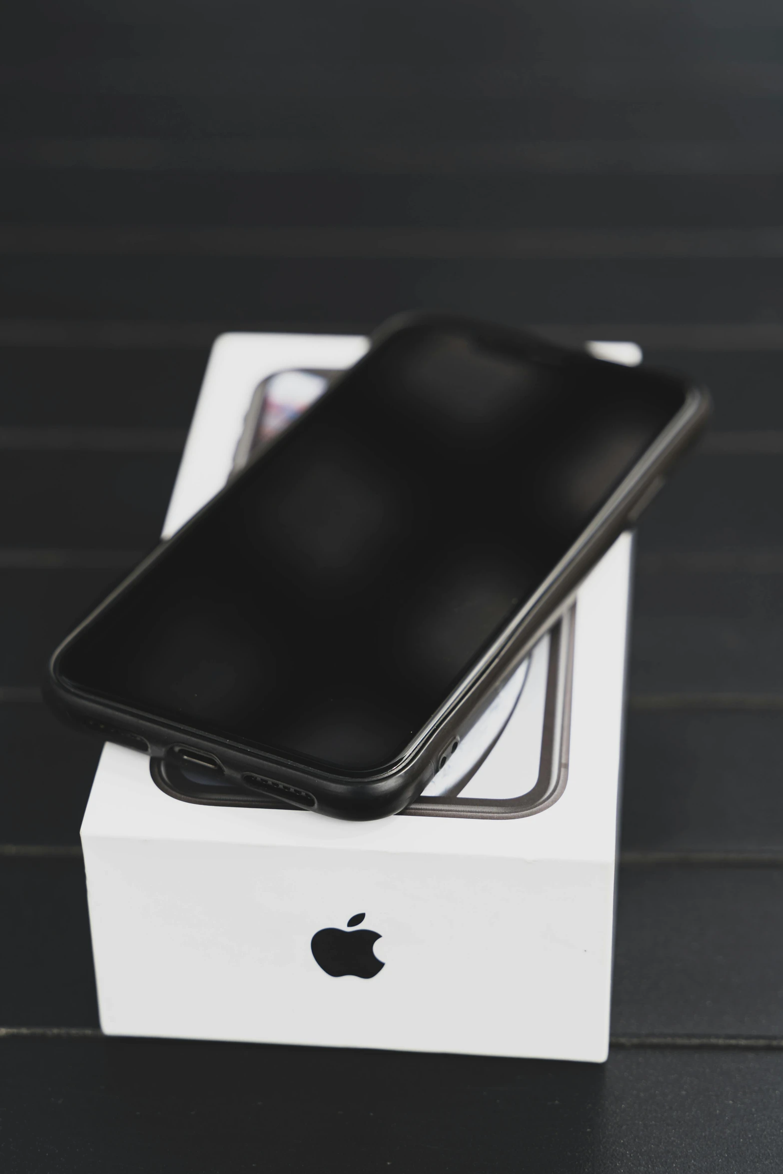 an iphone sitting on top of a box on a table, a picture, by Robbie Trevino, all black matte product, 256x256, low quality photo, 2717433015