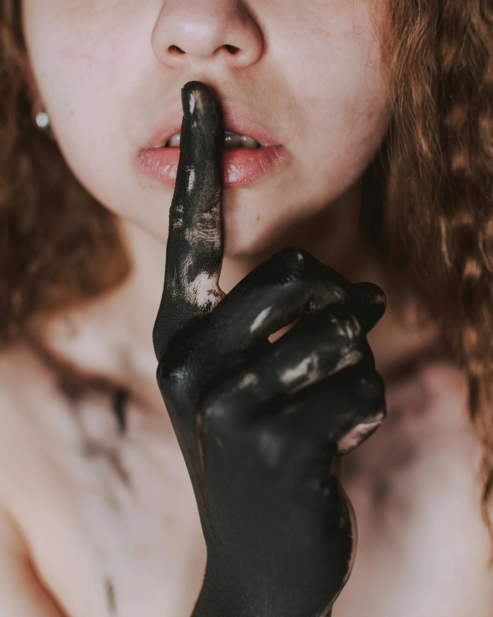 a close up of a person with a finger on their lips, an album cover, inspired by Hedi Xandt, trending on pexels, antipodeans, body painted with black fluid, sludge, hands up, non binary model