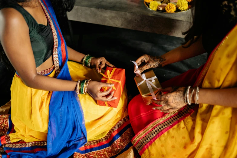 a couple of women sitting next to each other, pexels contest winner, hurufiyya, giving gifts to people, hindu aesthetic, primary colours, square