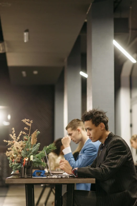 a group of people sitting at a table with laptops, by Matija Jama, pexels contest winner, arbeitsrat für kunst, elaborate hairstyles, fashion week backstage, kramskoi 4 k, flowers around